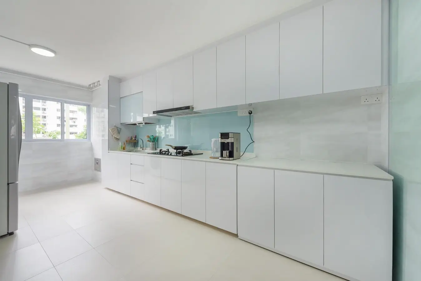 Full-height white kitchen cabinetry with glass backsplash