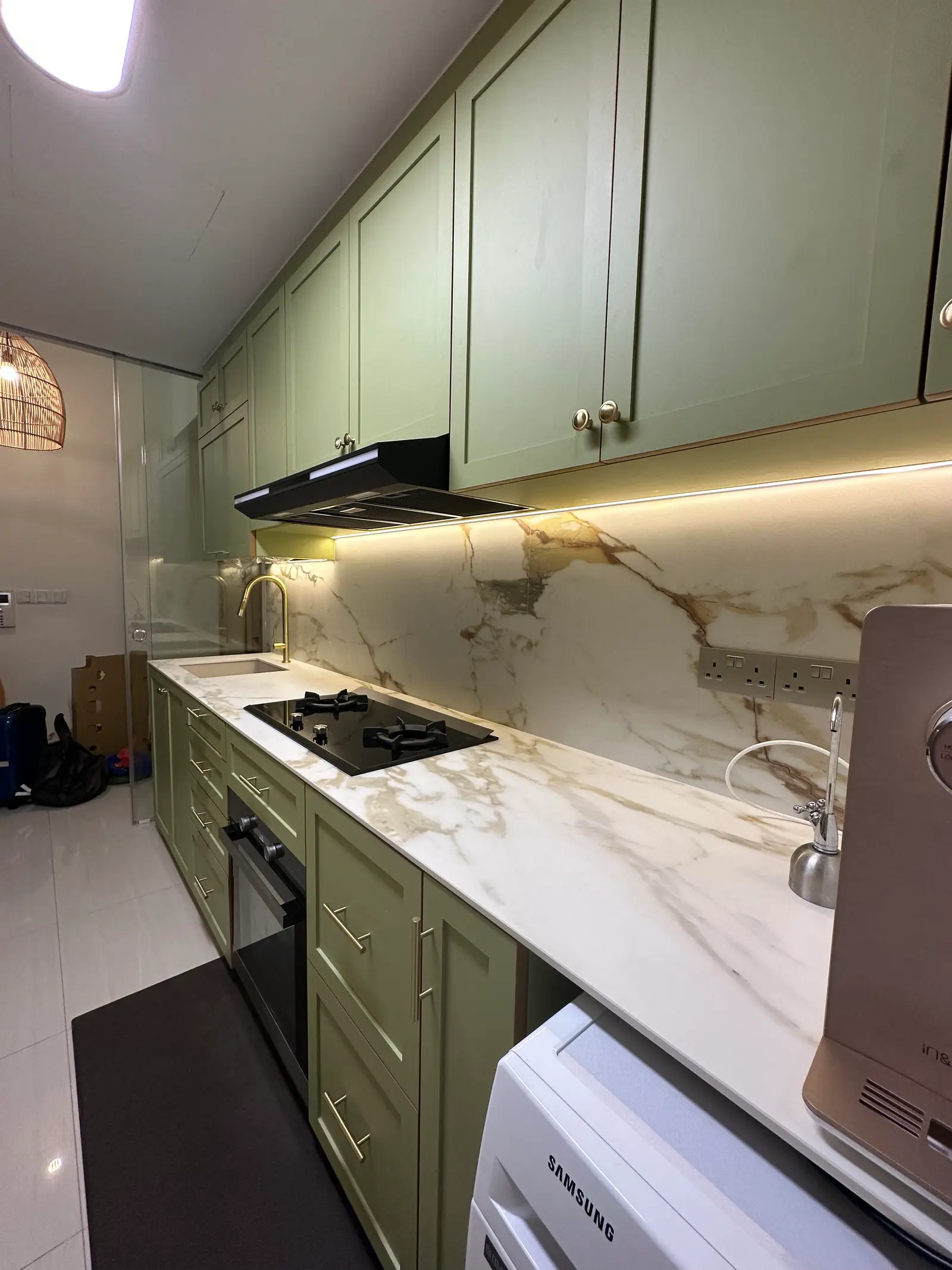 Sage green kitchen cabinetry coordinated with stone countertops and backsplash