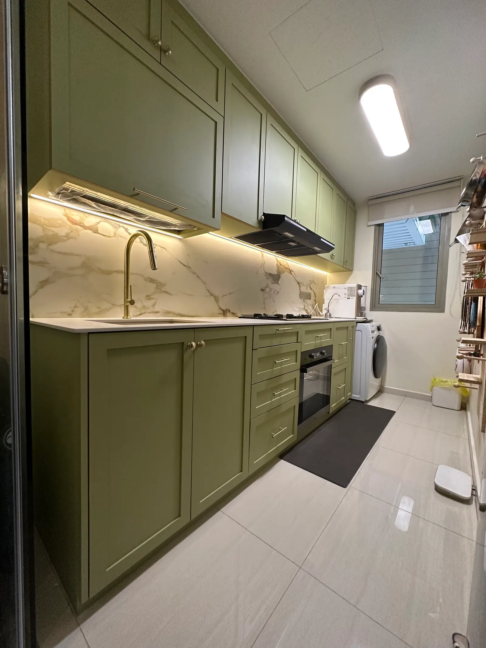 Sage green shaker kitchen with illuminated stone backsplash