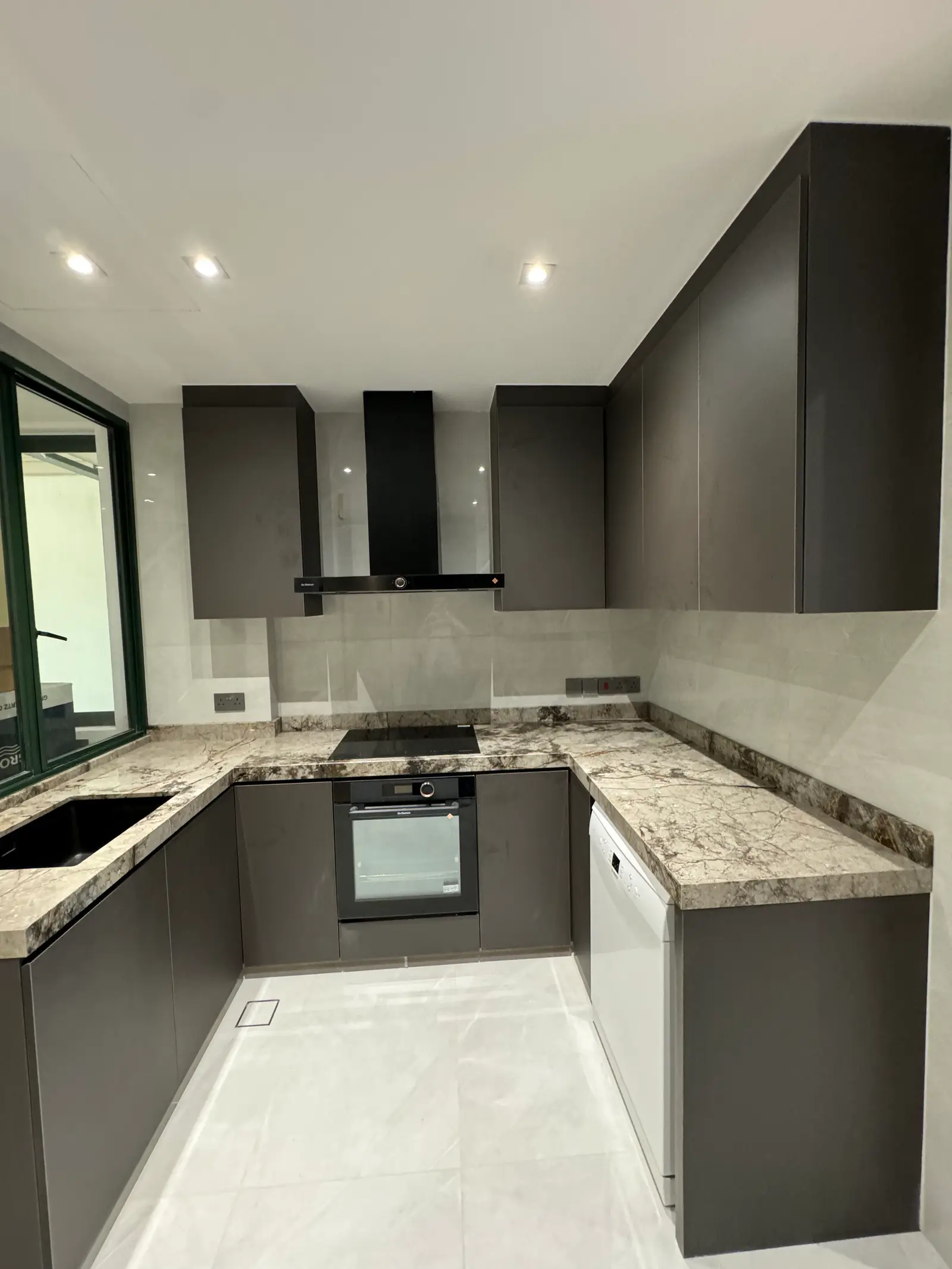 Dark handleless kitchen with natural stone countertops