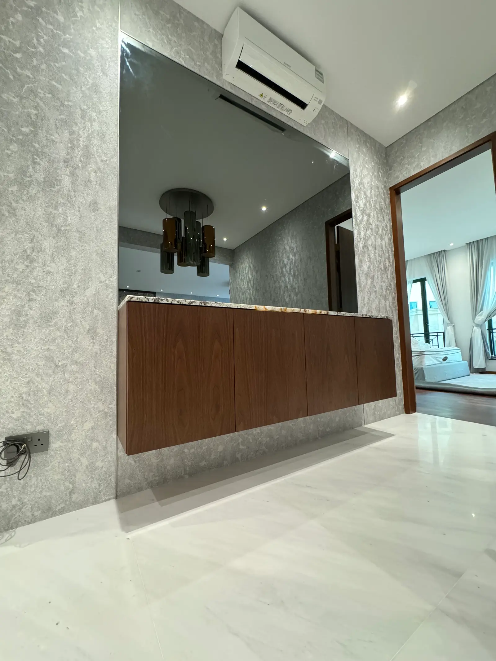 Floating walnut cabinet beneath a full-height mirror